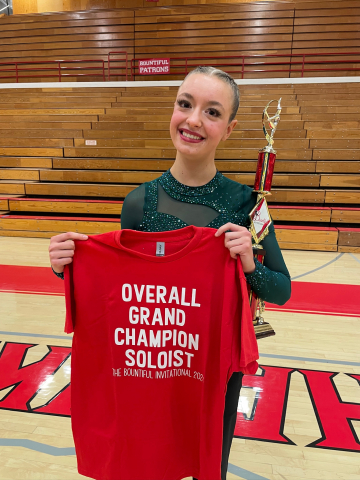 student with trophy and "Overall Grand Champion Soloist" t shirt