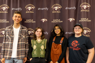 students standing in a row, smiling with a MMHS backdrop behind them
